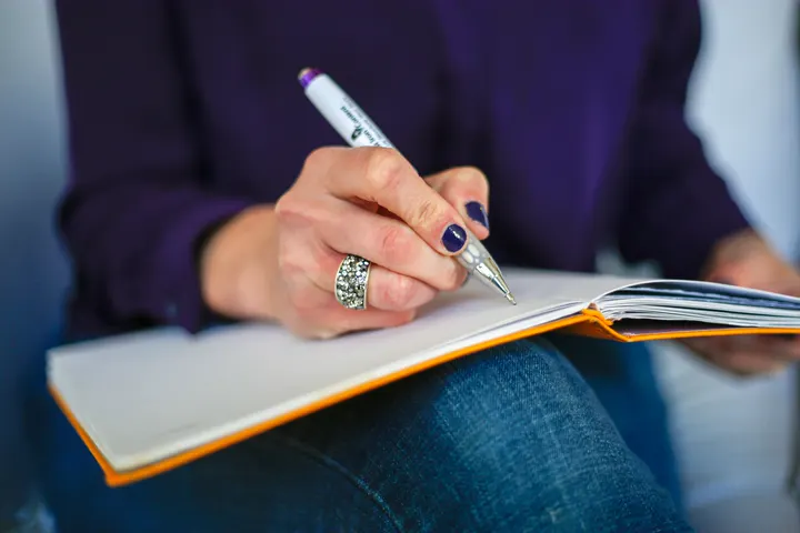 Illustrative close-up of a woman writing in a notebook