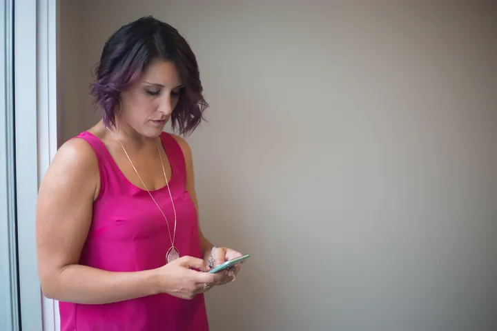 Illustrative photo of a woman composing a message on her phone