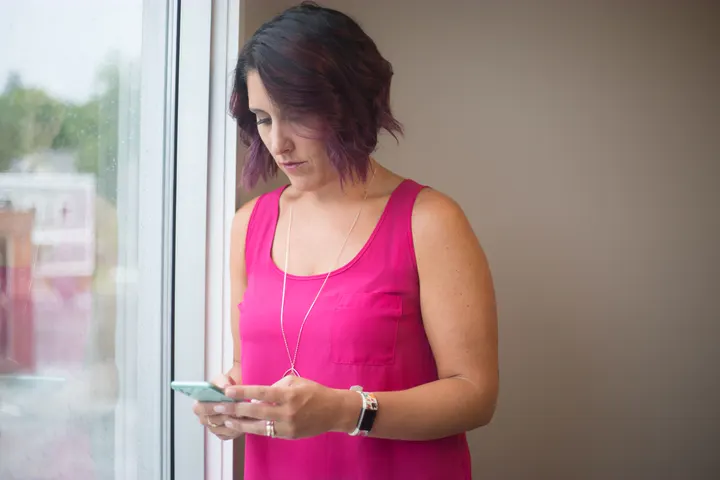 Illustrative photo of a woman reading her phone thoughtfully by a window