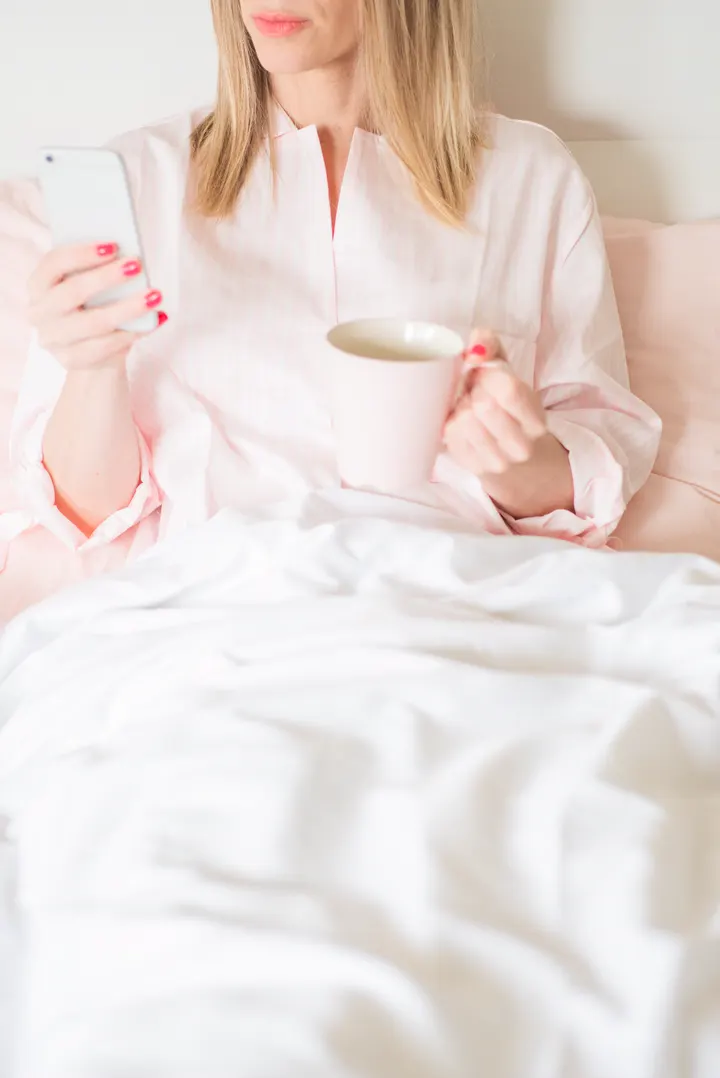 Illustrative photo of a woman alone with her phone and a cup of coffee
