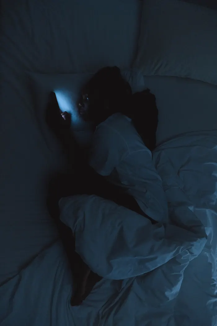 Illustrative scene: someone checking a phone in bed at night